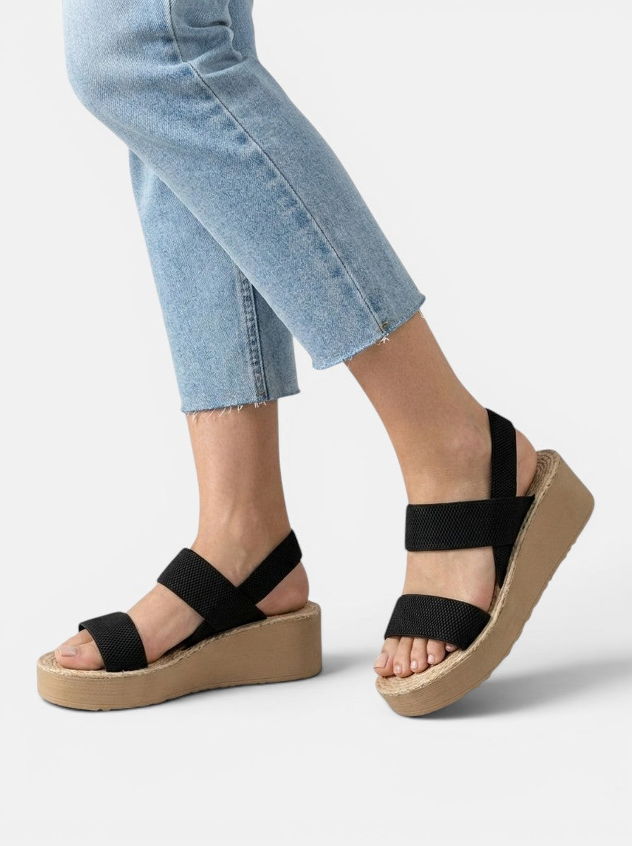 Venatte black elastic strap wedge sandals with espadrille sole and open toe. Worn with light wash jeans.