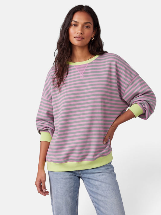 Model wearing a Venatte oversized pink and grey striped sweatshirt with lime green contrast trim and round neckline.